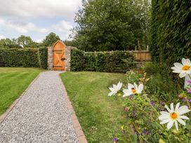 A gravel pathway leading to a wooden gate with stone walls surrounded by grass and flowering plants at Mistletoe Cottage in Kemeys Commander near Usk