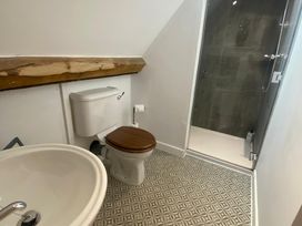 A bathroom with a toilet a sink a shower and patterned floor tiles at Mistletoe Cottage in Kemeys Commander near Usk