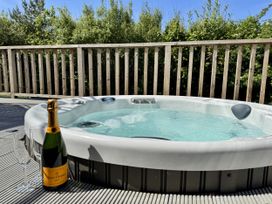 A hot tub with a champagne bottle and glass at The Black Barnacle in Portreath