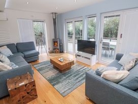 A living room with a sofa, television, and wood stove at The Black Barnacle in Portreath
