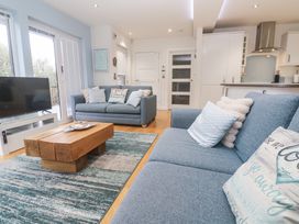 A living room with a sofa, coffee table, and television at The Black Barnacle in Portreath