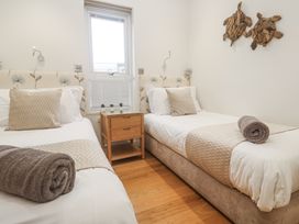 A bedroom with two beds and a bedside table at The Black Barnacle in Portreath