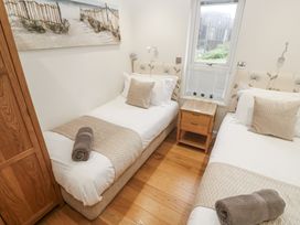 A bedroom with twin beds, a nightstand, and a window at The Black Barnacle Portreath