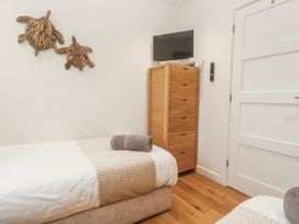A bedroom with twin beds and a television at The Black Barnacle in Portreath