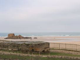 A view of a beach with a rock formation and people walking at The Black Barnacle in Portreath