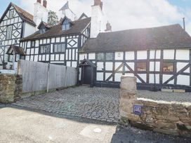 A cobblestone driveway and timber framed buildings with white and black walls at Wyre Court Cottage in Bewdley