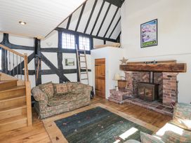 A living room with patterned sofas wooden stairs a brick fireplace and a framed poster at Wyre Court Cottage in Bewdley