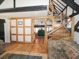 A living area with wooden staircase patterned sofa and wooden beams at Wyre Court Cottage in Bewdley