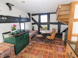 A kitchen area with a green stove table and chairs under wooden stairs at Wyre Court Cottage in Bewdley
