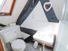 A bathroom with a toilet a sink a window and a heart shaped mirror at Wyre Court Cottage in Bewdley