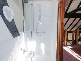 A shower with white tiles a heart shaped mirror and a wooden doorway leading to a stairway at Wyre Court Cottage in Bewdley