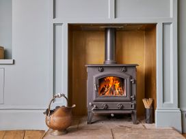 A living room with a wood stove and firewood at Isla House in Whitby
