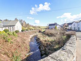 A small river running through a village with stone walls houses and a church at Minffordd in Pandy Tudur near Betws-Y-Coed