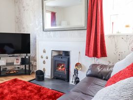 A living room with a fireplace a television a red rug and a brown sofa at Minffordd in Pandy Tudur near Betws-Y-Coed