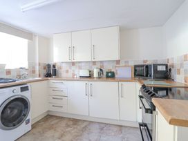 A kitchen with white cabinets wood countertops washing machine microwave toaster kettle and stove at Minffordd in Pandy Tudur near Betws-Y-Coed