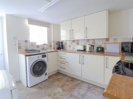 A kitchen with white cabinets a washing machine toaster kettle and microwave at Minffordd in Pandy Tudur near Betws-Y-Coed