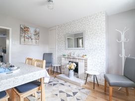A dining room with a table and chairs a fireplace with decorations a wall mirror and a coat rack at Minffordd in Pandy Tudur near Betws-Y-Coed