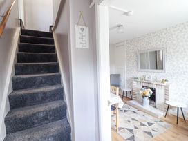 A staircase with dark carpet leading up and a dining room with a fireplace a mirror and patterned wallpaper at Minffordd in Pandy Tudur near Betws-Y-Coed