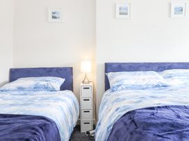 A bedroom with two beds separated by a small white nightstand with a lamp at Minffordd in Pandy Tudur near Betws-Y-Coed