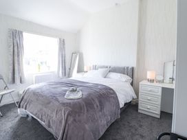A bedroom with a double bed a bedside table with a lamp and mirror and a window with curtains at Minffordd in Pandy Tudur near Betws-Y-Coed