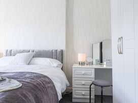 A bedroom with a bed a bedside table lamp a dressing table with a stool and a wardrobe at Minffordd in Pandy Tudur near Betws-Y-Coed