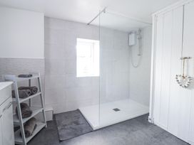 A bathroom with a walk-in shower, towels on a small shelf, a window, and a white door at Minffordd in Pandy Tudur near Betws-Y-Coed