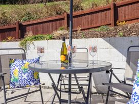 An outdoor patio with a glass table four chairs a bottle of prosecco and four patterned glasses at Minffordd in Pandy Tudur near Betws-Y-Coed