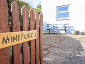 A wooden gate with a Minffordd sign and a paved area with a bench and cushions at Minffordd in Pandy Tudur near Betws-Y-Coed