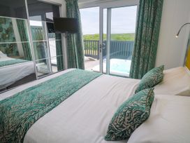 A bedroom with a bed and balcony at Dahlia in Portreath