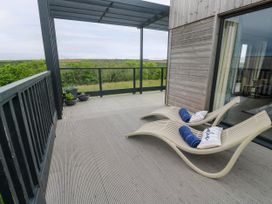 An outdoor terrace with two sun loungers and potted plants at Dahlia in Portreath