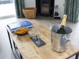 A living room with a coffee table featuring champagne and snacks at Dahlia in Portreath