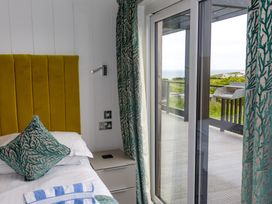 A bedroom with a bed and outdoor view at Dahlia in Portreath