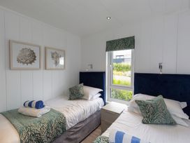A bedroom with two single beds and wall art at Dahlia in Portreath