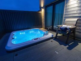 An outdoor area with a hot tub and a chair at Dahlia in Portreath