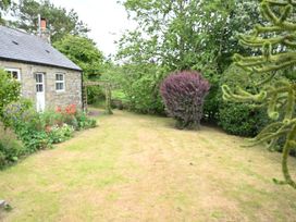 A garden with a stone house and various plants at Petty Knowes Cottage Rochester near Otterburn