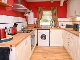 A kitchen with wooden cabinets and appliances at Petty Knowes Cottage Rochester near Otterburn