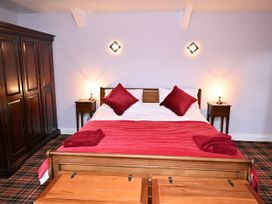 A bedroom with a bed, wardrobe, and bedside table at Petty Knowes Cottage near Rochester