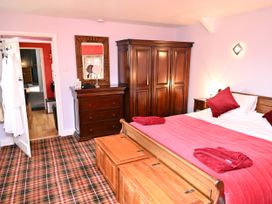 A bedroom with a bed, wardrobe, and dresser at Petty Knowes Cottage in Rochester near Otterburn