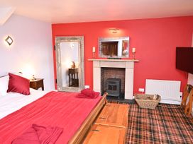 A bedroom with a bed and fireplace at Petty Knowes Cottage Rochester near Otterburn