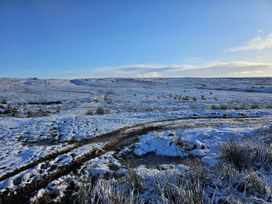 A snowy field with sheep and a muddy path at Petty Knowes Cottage Rochester near Otterburn