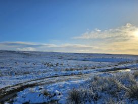 A snowy landscape with sheep grazing and a stream at Petty Knowes Cottage Rochester near Otterburn
