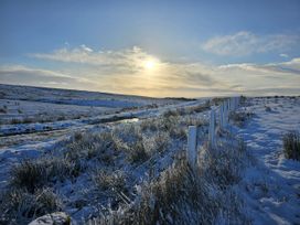 A snowy landscape with a fence and road at Petty Knowes Cottage near Rochester