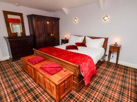 A bedroom with a bed, nightstand, and wardrobe at Petty Knowes Cottage Rochester near Otterburn