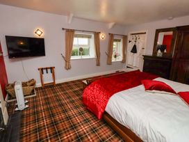 A bedroom with a bed and television at Petty Knowes Cottage in Rochester near Otterburn