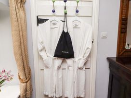 A bathroom with robes and a hairdryer bag hanging on a door at Petty Knowes Cottage Rochester near Otterburn