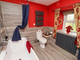 A bathroom with a bathtub, toilet, and window at Petty Knowes Cottage, Rochester near Otterburn