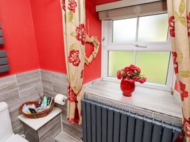 A bathroom with a toilet and flower vase at Petty Knowes Cottage near Rochester