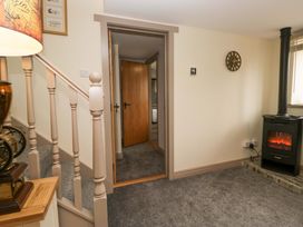 A hallway with a staircase and an electric fireplace at Yeat Stoup Cottage in Cockermouth