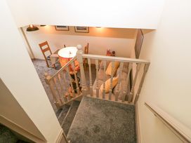 A staircase leading to a hallway with a table and sofa at Yeat Stoup Cottage Cockermouth