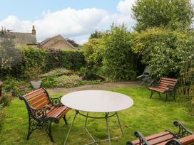 A garden with a table and chairs at Yeat Stoup Cottage in Cockermouth